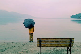 Man with Umbrella Standing by Lake Bench