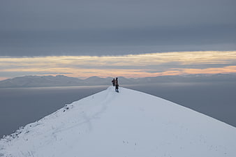 Hikers on Snowy Mountain Ridge at Sunset