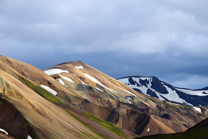 Colorful mountain landscape with snow patches and dramatic sky