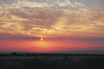 Dramatic sunset over distant mountains and open fields