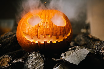 Spooky Jack-O-Lantern Pumpkin on Logs with Smoke