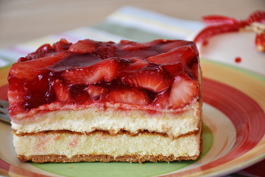 Close-up of layered strawberry cream cake slice on colorful plate