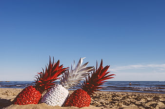 Painted red and white pineapples on a sunny beach