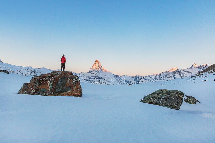 Hiker on Rock Viewing Matterhorn in Snowy Alps