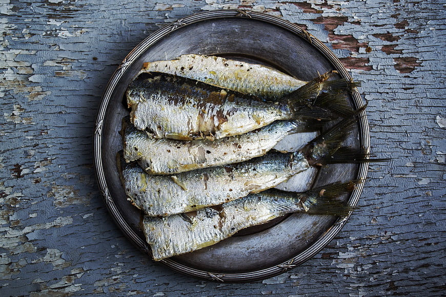 Grilled sardines on rustic metal plate