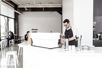 Barista preparing coffee in modern minimalist cafe interior