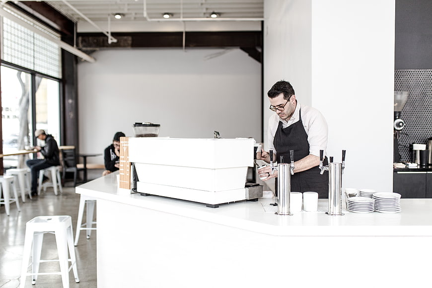 Barista preparing coffee in modern minimalist cafe interior