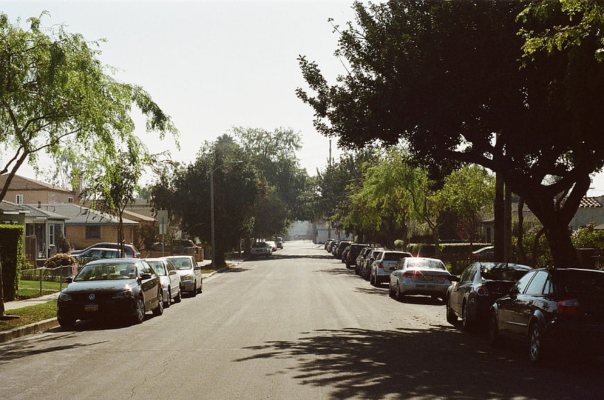 Quiet suburban street with parked cars and trees