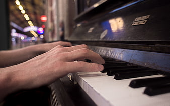 Close-up of hands playing an old upright piano at night