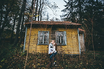 Romantic couple embracing in front of old yellow wooden house