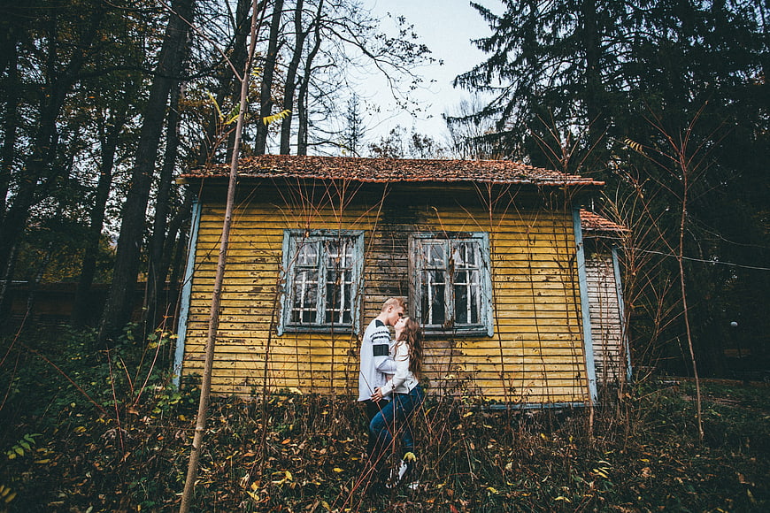 Romantic couple embracing in front of old yellow wooden house
