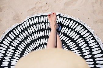 Woman relaxing on beach towel with straw hat