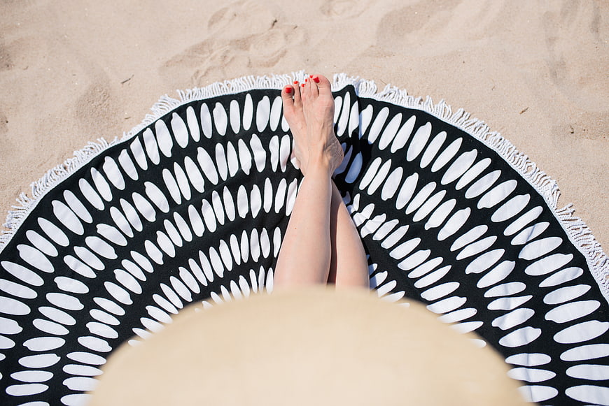 Woman relaxing on beach towel with straw hat