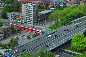 Aerial view of red tram crossing highway in city