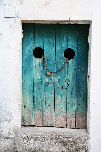 Old weathered teal wooden door with padlock and chain