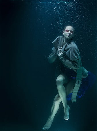 Underwater fashion portrait of a woman in a dark blue aquatic environment
