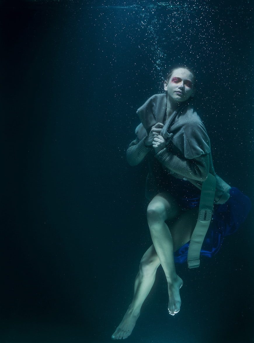 Underwater fashion portrait of a woman in a dark blue aquatic environment