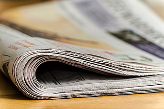 Close-up of folded newspaper pages on wooden table