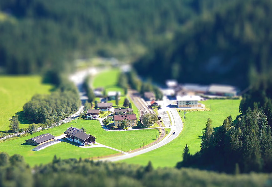 Tilt-shift aerial view of alpine village with train tracks