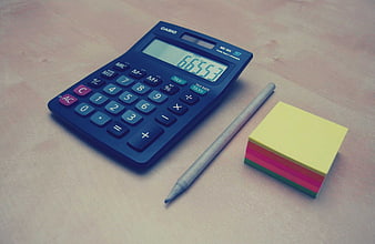 Blue calculator, pen, and sticky notes on wooden desk