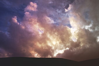 Dramatic sunset clouds over dark mountain silhouette