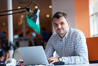 Smiling man working on laptop in modern office