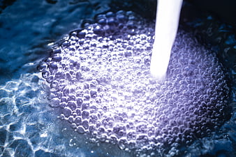 Close-up of water stream creating purple bubbles