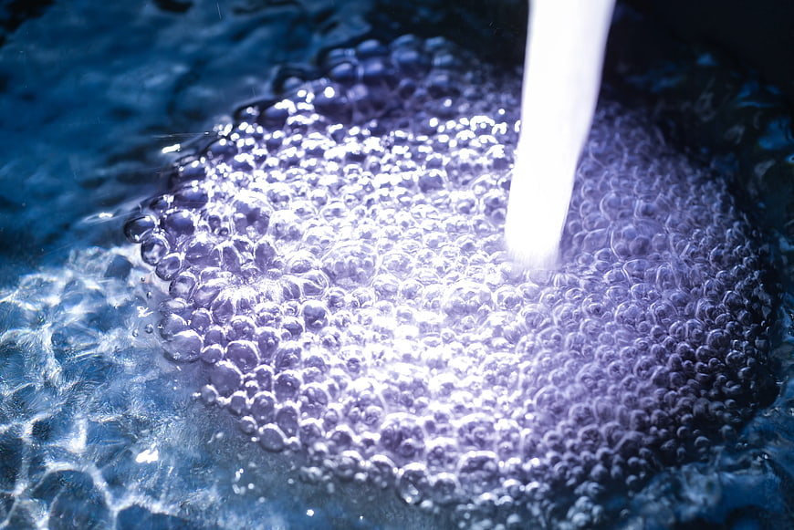 Close-up of water stream creating purple bubbles