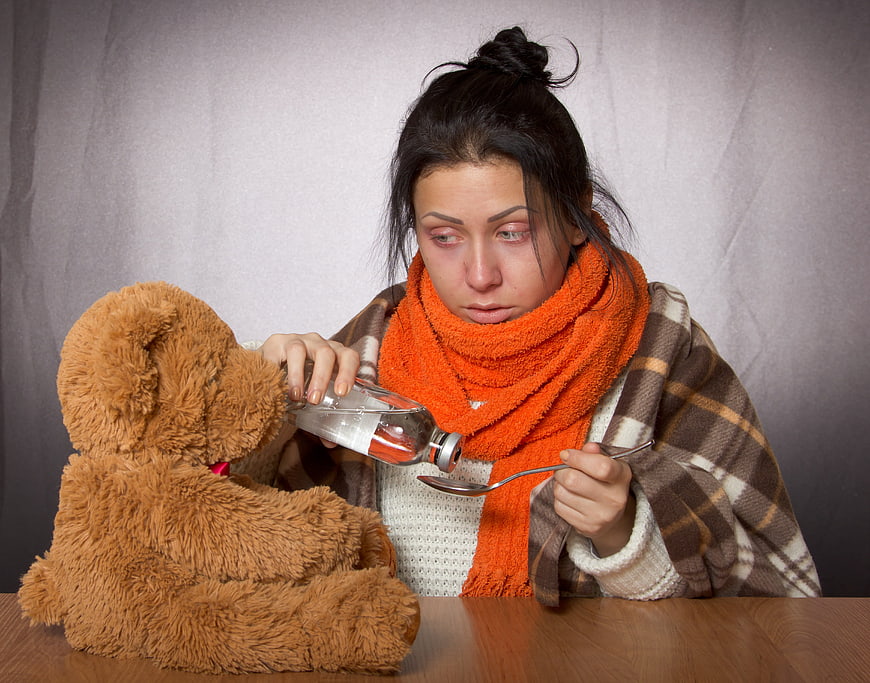 Sick woman giving medicine to teddy bear