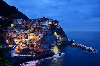 Colorful coastal village on cliff at twilight with illuminated houses