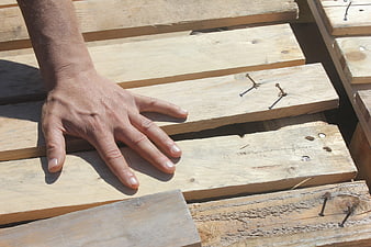 Carpenter's Hand Resting On Weathered Wooden Planks With Nails