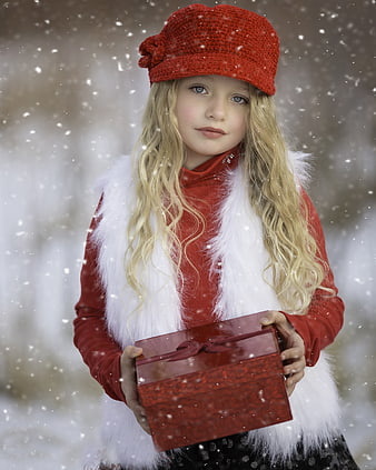 Young Girl in Red Hat Holding Gift Box in Snow