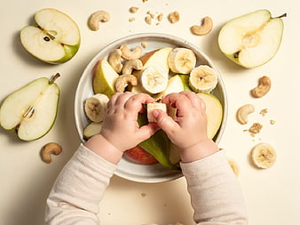 Toddler Hands Eating Fresh Fruit and Nuts Snack
