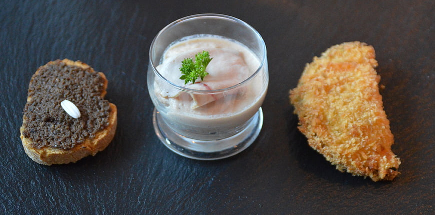 Gourmet appetizer trio on dark slate with caviar, mousse, and croquette