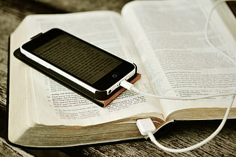 Smartphone with e-book app resting on open physical Bible