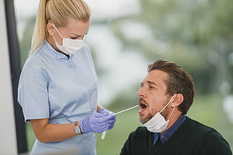 Nurse performing nasal swab test on male patient