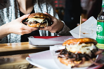 Hands holding pulled pork burger with beer bottle