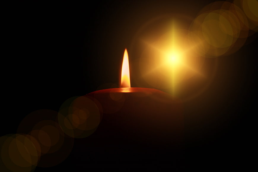 Glowing Candle Flame With Bokeh Lights Against Dark Background