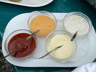 Assorted condiments in glass bowls on a white tray