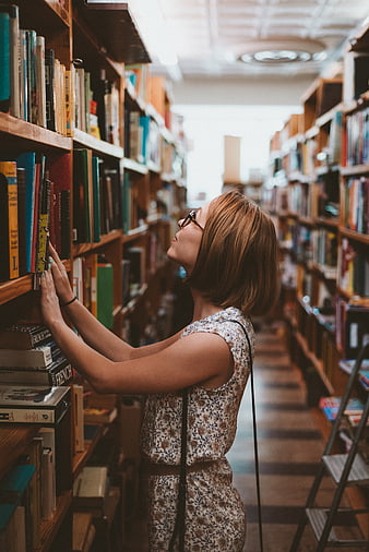 Woman browsing books in a cozy library aisle