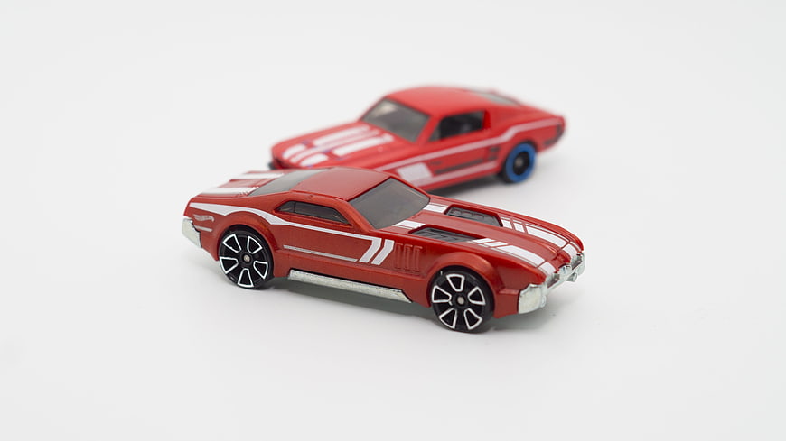 Two red toy muscle cars on white background