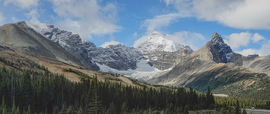 Panoramic View of Snow-Capped Mountain Peaks and Pine Forest