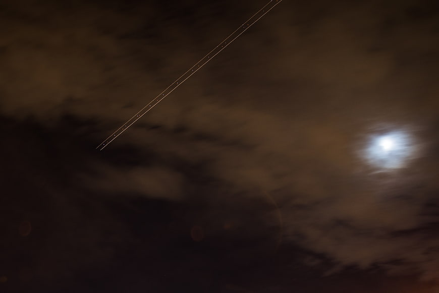 Long exposure night sky with moon and airplane light trail