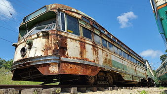 Rusted vintage electric tram car abandoned on railway tracks