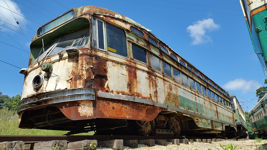 Rusted vintage electric tram car abandoned on railway tracks