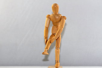 Wooden Art Mannequin Posing with Raised Leg on White Background