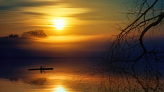 Silhouette of Kayaker on Misty Lake at Golden Sunrise