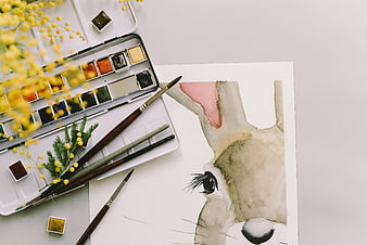 Watercolor bunny painting with art supplies and mimosa flowers