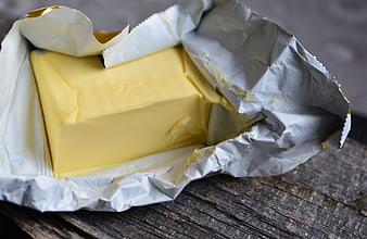 Block of butter in foil wrapper on rustic wood