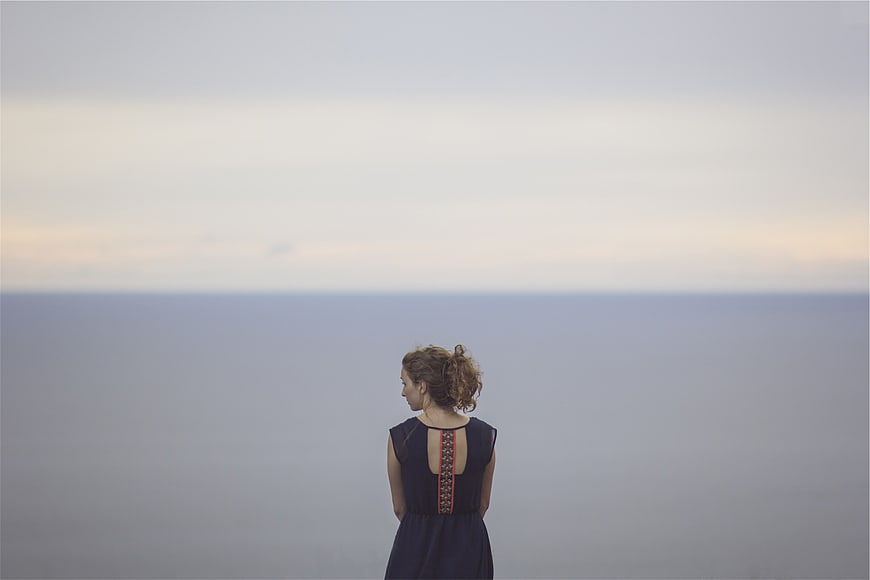 Woman in Blue Dress Looking Out at Calm Sea Horizon